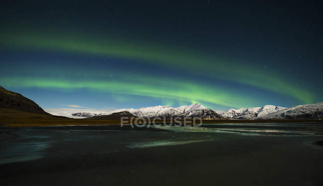 Colorful Aurora borealis over snowy mountainscape, Iceland — Stock Photo