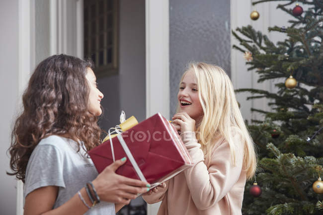 Girl handing over Christmas present to friend — Stock Photo