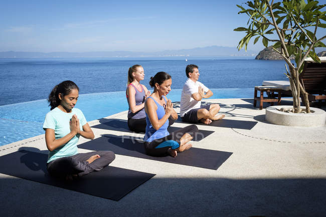 Yoga group exercising at ocean front resort — Stock Photo