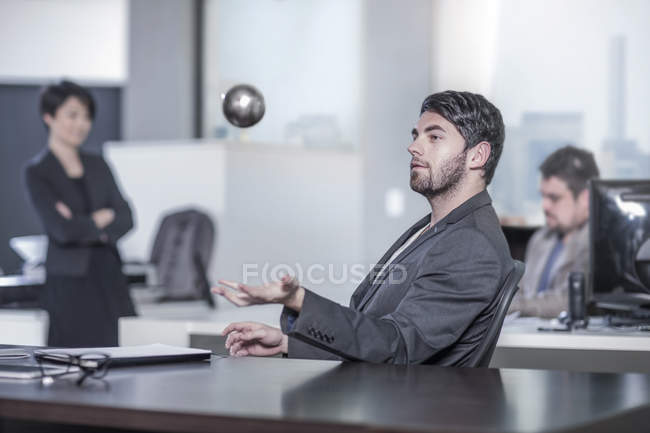 New York city office, man sitting at desk in city office throwing a ball in the air — Stock Photo