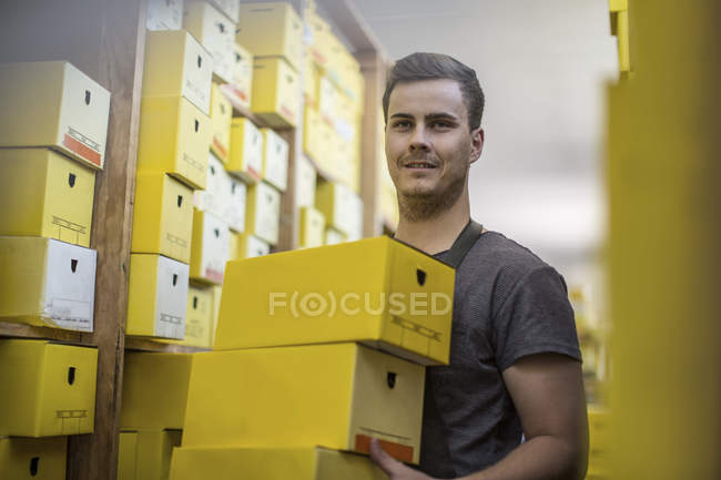 Young man in warehouse carrying shoe boxes — Stock Photo