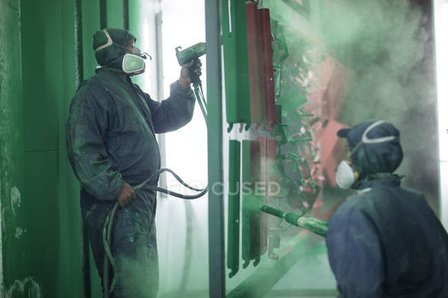 Painters spraying steel components in spray booth of a factory — Stock Photo