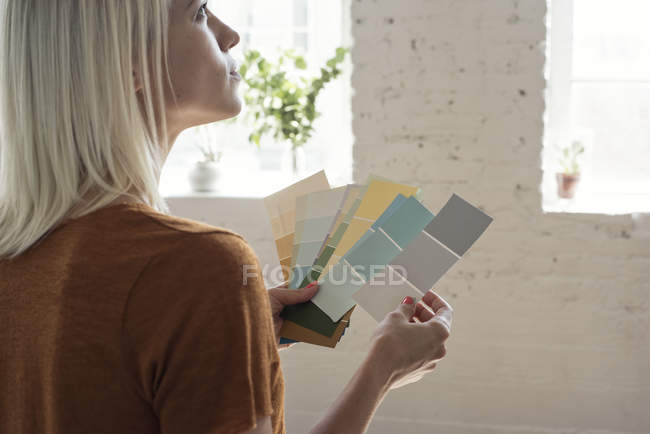 Jeune femme dans un loft penser à des échantillons de couleur — Photo de stock