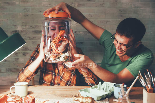 Casal jovem se divertindo com estatuetas de animais no frasco — Fotografia de Stock