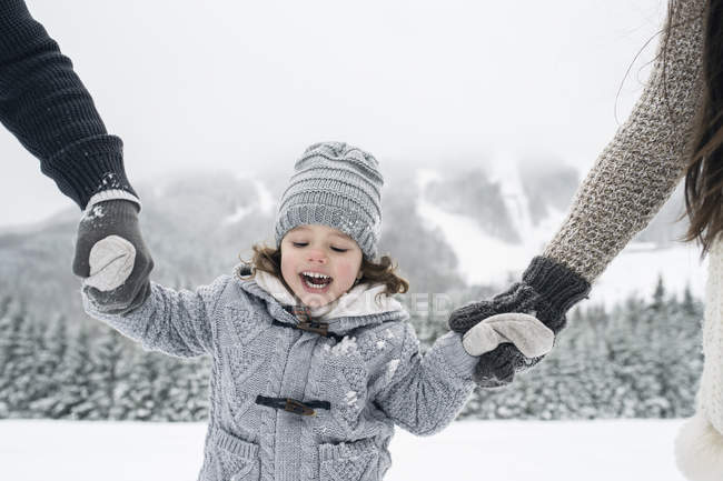 Chica feliz de la mano con los padres en el paisaje de invierno - foto de stock