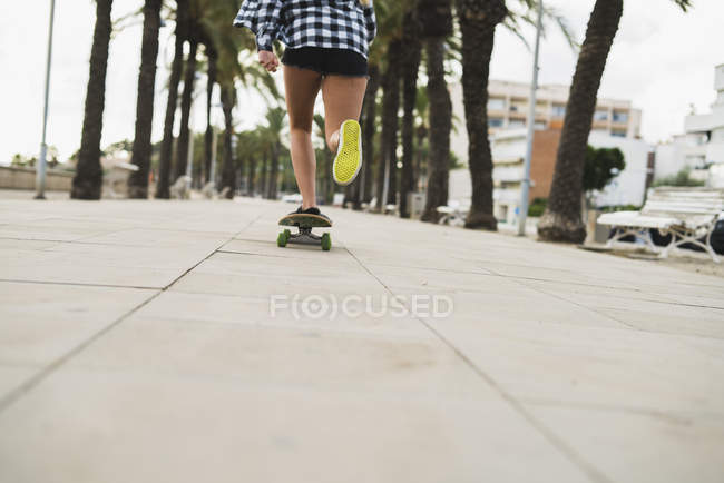 Femme skateboard sur ruelle avec palmiers — Photo de stock