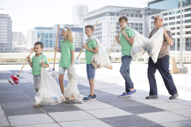 Group of volunteering children collecting garbage with litter sticks — Stock Photo