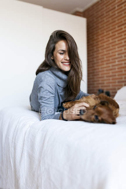 Jeune femme caucasienne attrayante caressant chien sur le lit — Photo de stock