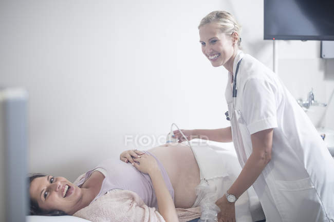 Doctor in hospital doing sonogram with pregnant woman — Stock Photo