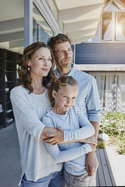 Happy family standing on terrace, embracing daughter — Stock Photo