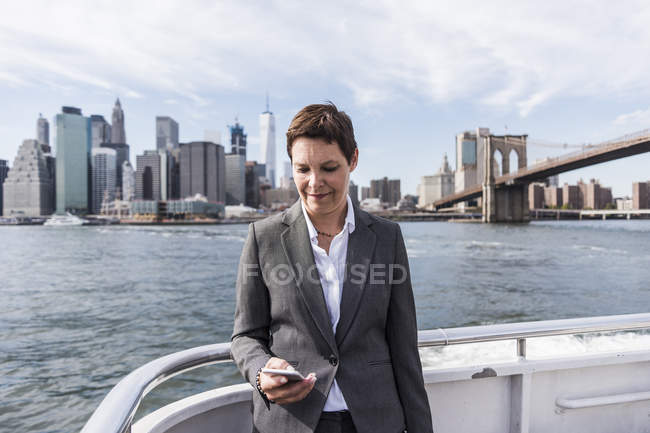 Businesswoman standing on boat and using cell phone, Brooklyn, Stati Uniti d'America — Foto stock
