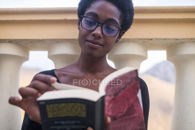 Розумна приваблива афроамериканська дівчина в окулярах читає книгу — стокове фото
