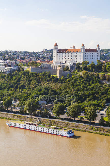 Slovakia, Bratislava, view to castle with river cruise ship on the Danube in the foreground — Stock Photo