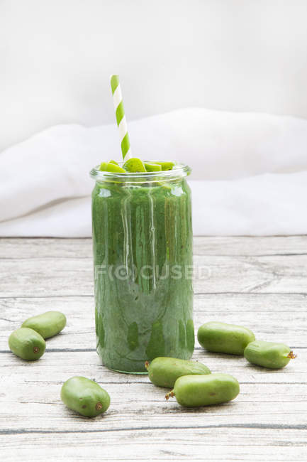 Vaso di kiwi verde resistente frullato su legno grigio con ingrediente — Foto stock