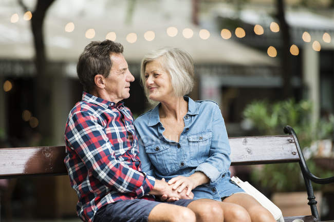 Happy senior couple hugging each other on bench at park — Stock Photo