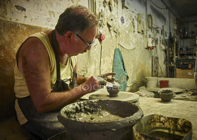 Ceramista in officina che lavora su recipiente di terracotta — Foto stock