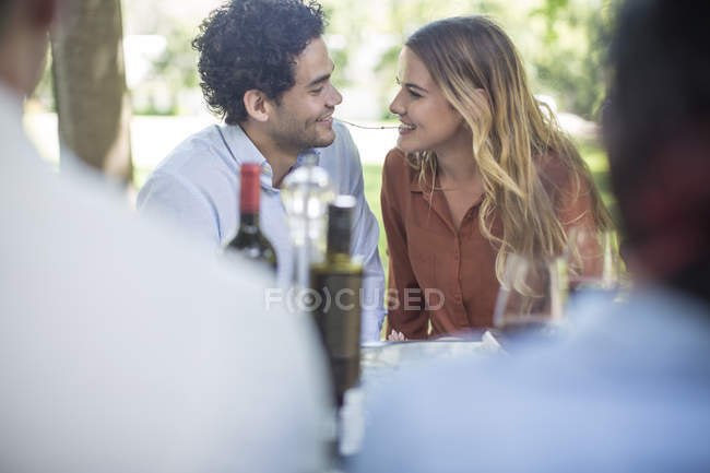 Junges Paar sitzt mit Flasche Wein vor dem Mittagessen im Garten — Stockfoto