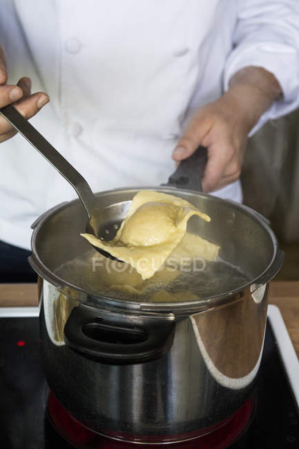 Homme cuisine raviolis dans une casserole dans une cuisine — Photo de stock
