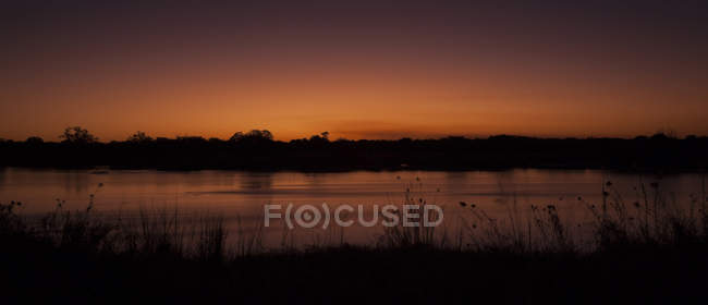 Namibia, puesta de sol en Okavango sobre el campo y el lago - foto de stock