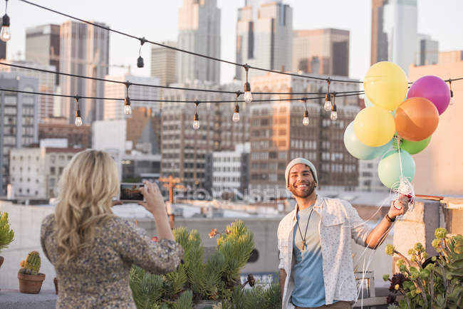 Woman taking photo of man at rooftop party, Los Angeles, USA — Stock Photo