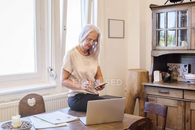 Geschäftsfrau arbeitet im Homeoffice mit Smartphone und Laptop — Stockfoto