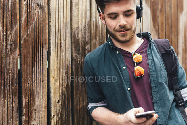 Junger Mann hört Musik über Kopfhörer und benutzt Smart — Stockfoto