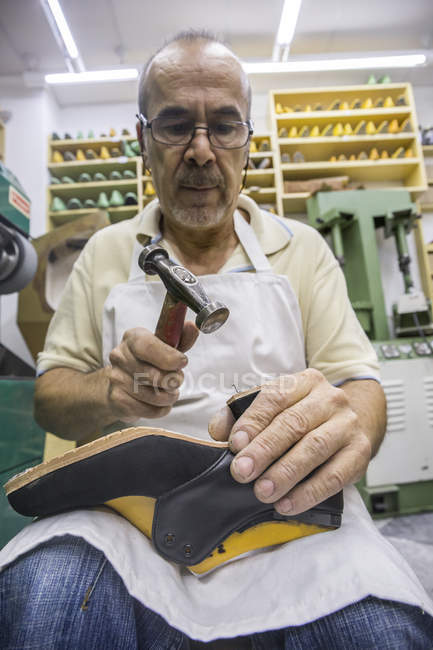 Shoemaker working with hammer on shoe in his workshop — Stock Photo