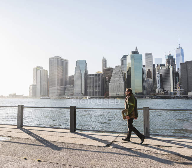 États-Unis, Brooklyn, homme d'affaires avec mallette marchant devant Manhattan skyline — Photo de stock