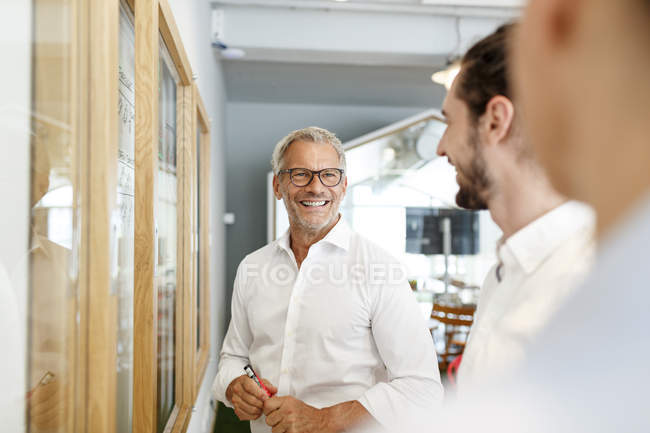 Homme d'affaires souriant regardant ses collègues au bureau — Photo de stock