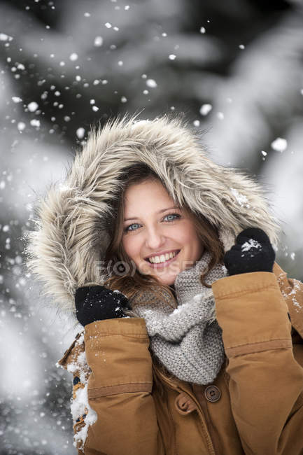 Молодая женщина в меховом капюшоне в снегопаде, портрет — стоковое фото