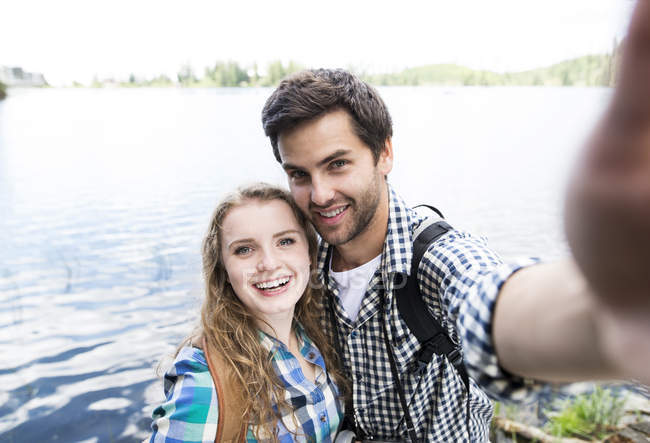 Jeune couple en randonnée sur un lac en selfie — Photo de stock