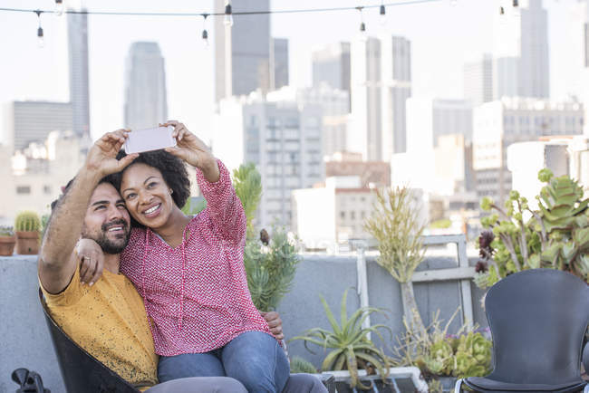 Couple taking selfie sitting at rooftop, Los Angeles, USA — Stock Photo