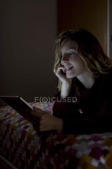 Жінка, лежачи на ліжку вночі за допомогою планшетного ПК — стокове фото