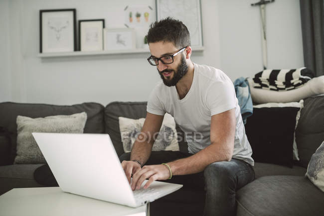 Hombre joven casual usando un portátil en casa - foto de stock