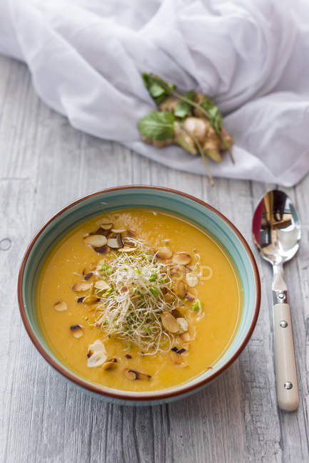 Bowl of sweet potato coconut soup with ginger, parsnip, leek, sprouts and almond — Stock Photo