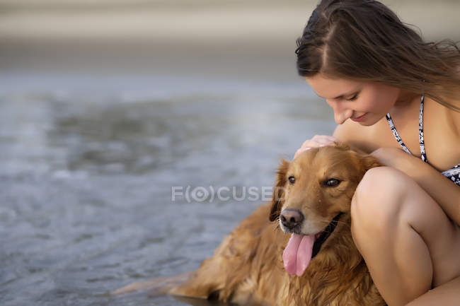 Крупним планом молоду жінку в бікіні, гладив її золотистий ретрівер собака на пляжі — стокове фото