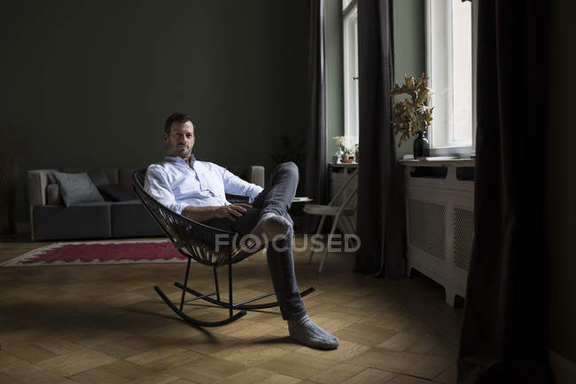 Porträt eines Mannes auf Schaukelstuhl im Wohnzimmer — Stockfoto