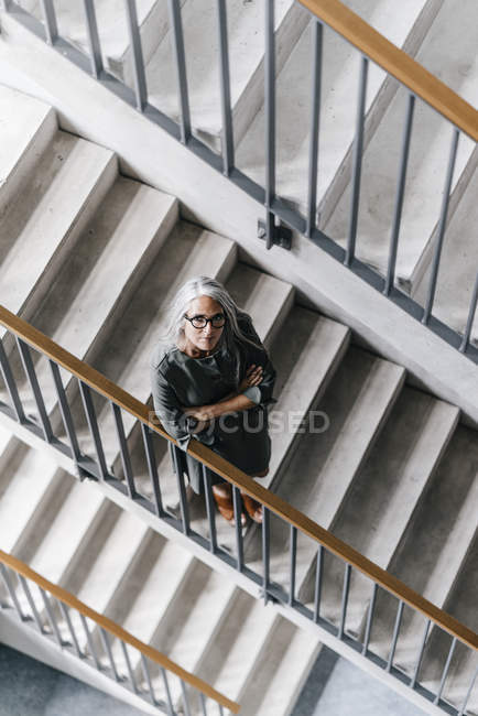 Frau mit langen grauen Haaren steht im Treppenhaus — Stockfoto