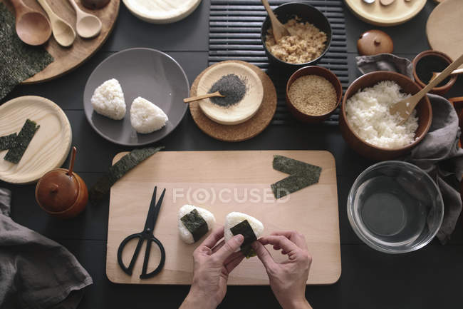Manos femeninas preparando sushi Onigiris, vista superior - foto de stock