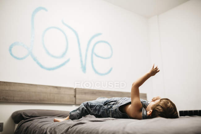Kleiner Junge spielt auf dem Bett seiner Eltern — Stockfoto