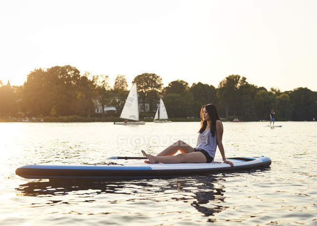 Jovem mulher em paddleboard desfrutando de pôr do sol de verão — Fotografia de Stock