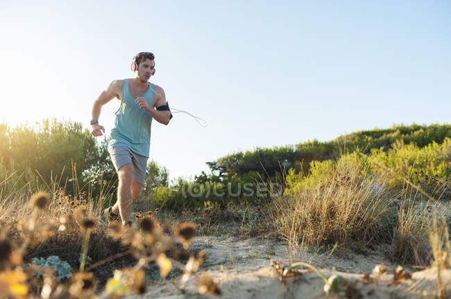 Junger Mann joggt bei Sonnenaufgang in Dünen — Stockfoto