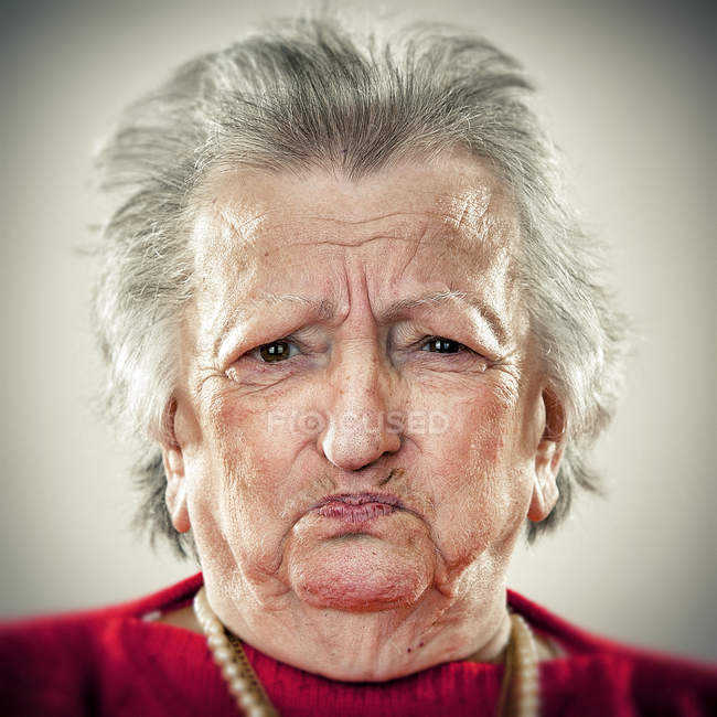Retrato de mujer mayor tirando de la cara y mirando a la cámara - foto de stock