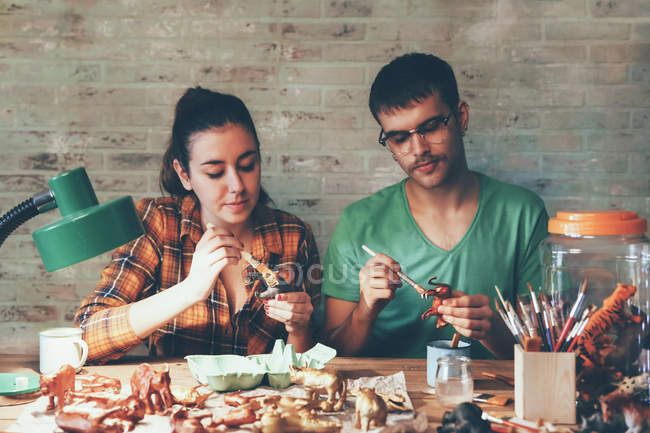 Jovem casal pintando figuras de animais com tinta — Fotografia de Stock