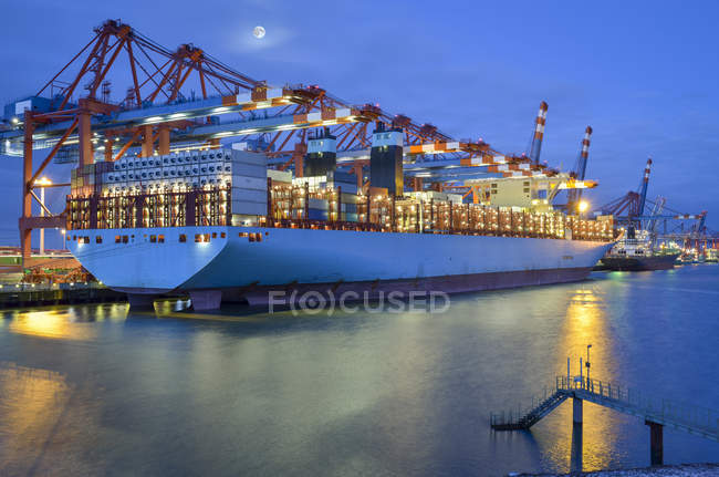 Porto industriale di Amburgo con portacontainer e gru illuminate al crepuscolo, Germania — Foto stock