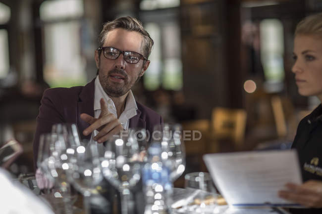 Uomo d'affari seduto alla scrivania con bicchieri di vino e cliente — Foto stock