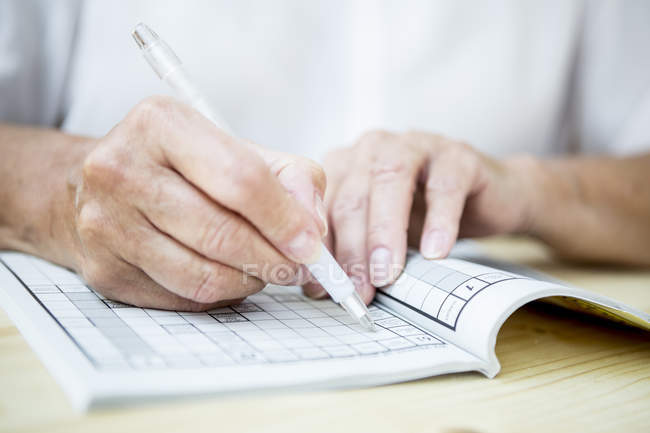 Nahaufnahme einer Seniorin beim Kreuzworträtsel — Stockfoto