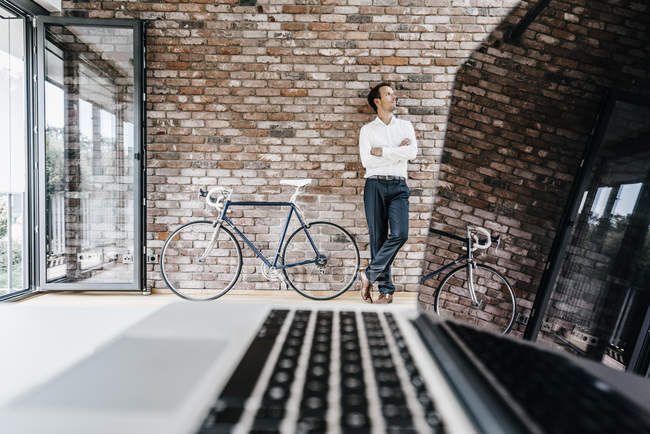 Geschäftsmann steht mit Fahrrad in modernem Büro — Stockfoto