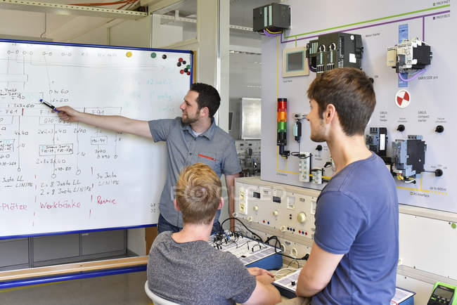 Students looking at technical instructor at whiteboard — Stock Photo