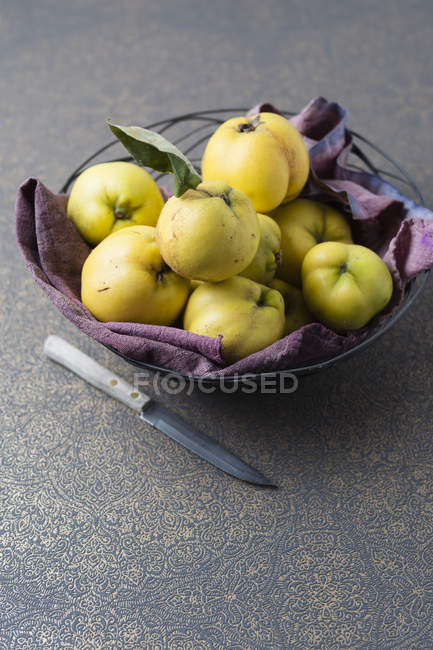 Fruit bowl of quinces and knife on table — Stock Photo